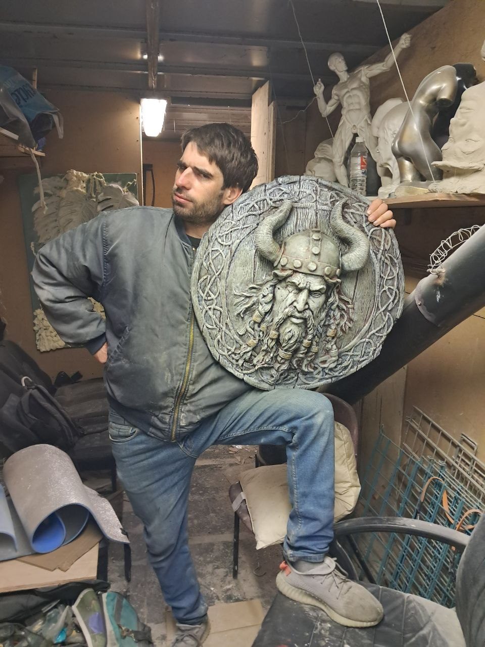 The maker in the studio holding a finished medallion